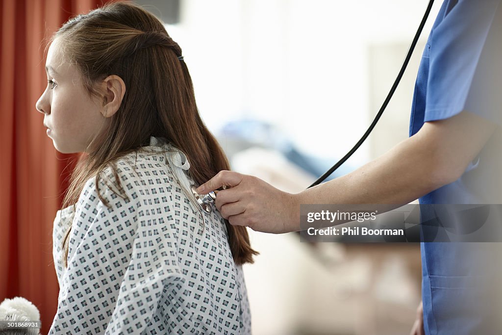 Nurse using stethoscope on girl