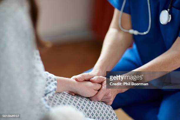 cropped image of nurse holding patient's hand - hospital uk stockfoto's en -beelden