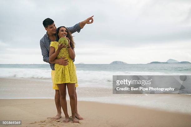 romantic young couple on ipanema beach, rio de janeiro, brazil - 2 coconut drinks ストックフォトと画像
