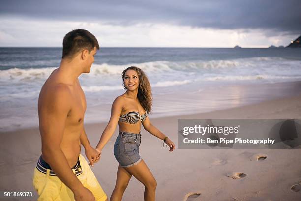 romantic young couple strolling on ipanema beach, rio de janeiro, brazil - swimming trunks stock pictures, royalty-free photos & images