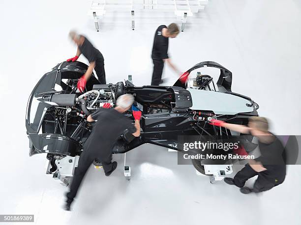 engineers assembling supercar in sports car factory, overhead view - koordination stock-fotos und bilder