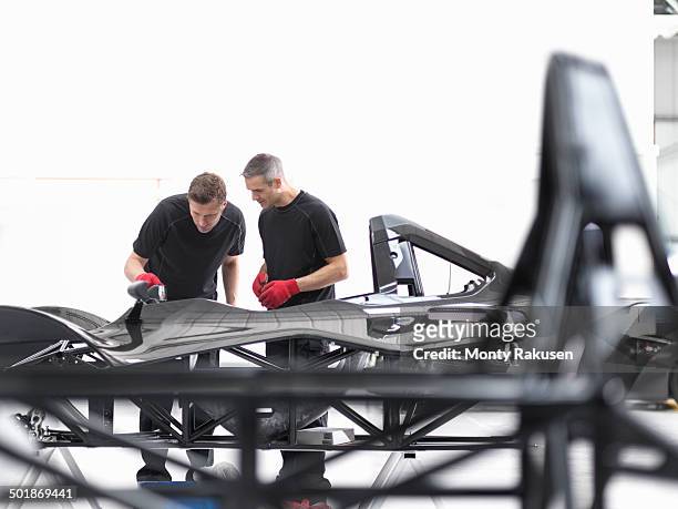 engineers inspecting carbon fibre car body shell in sports car factory - carbon fibre stockfoto's en -beelden
