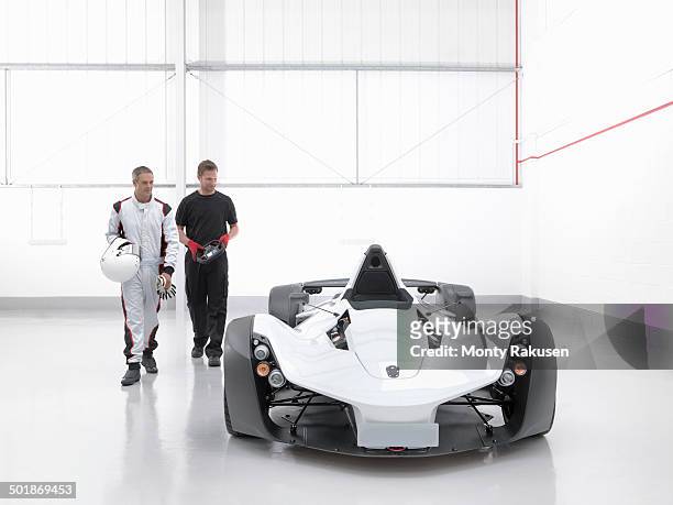 racing driver with engineer and supercar in car factory - white jumpsuit stock-fotos und bilder