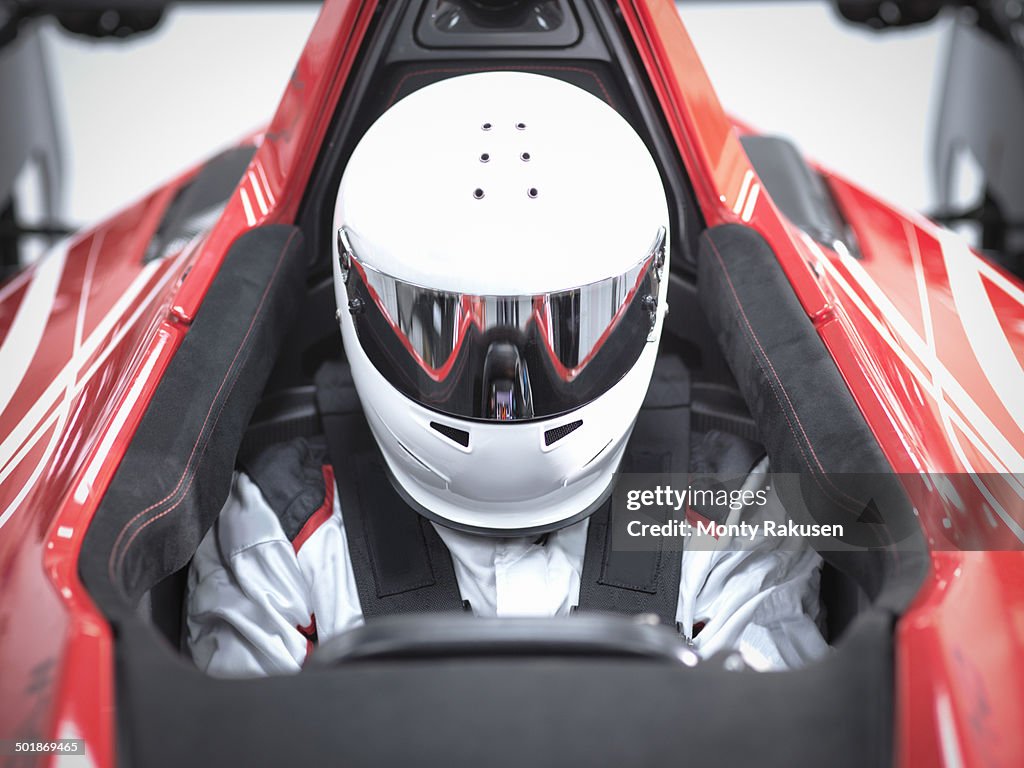 Racing driver wearing crash helmet in supercar