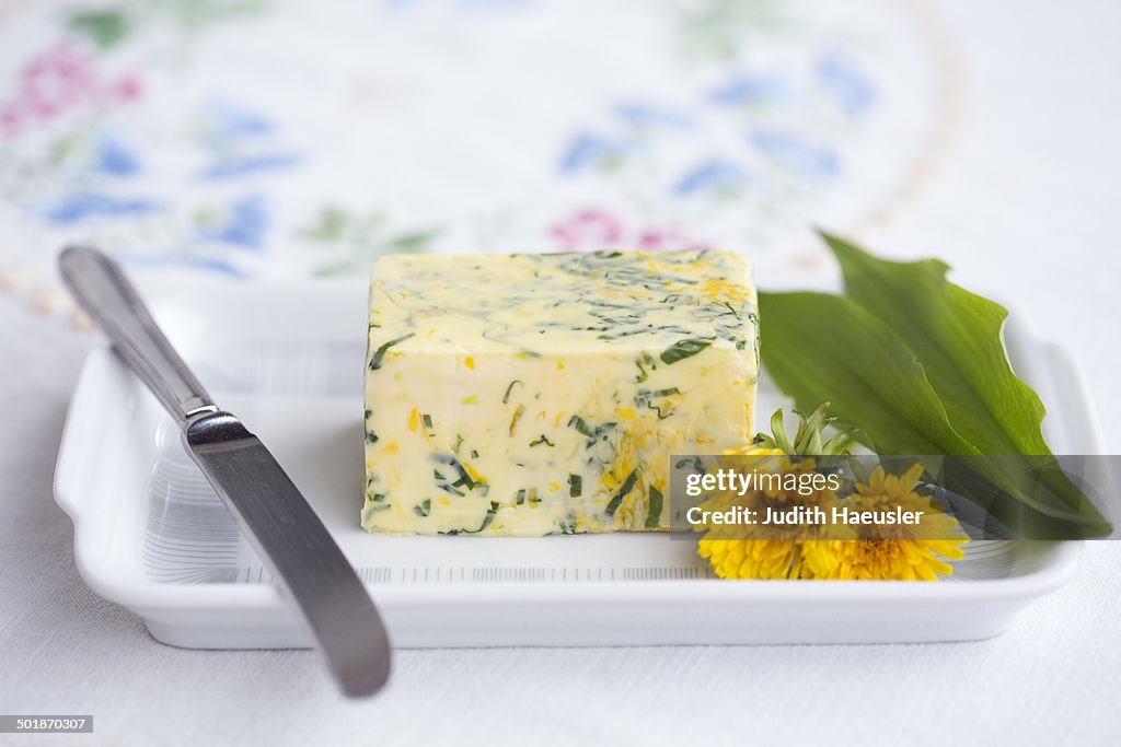 Wild garlic (Allium ursinum) butter with dandelion flower and leaves on butterdish