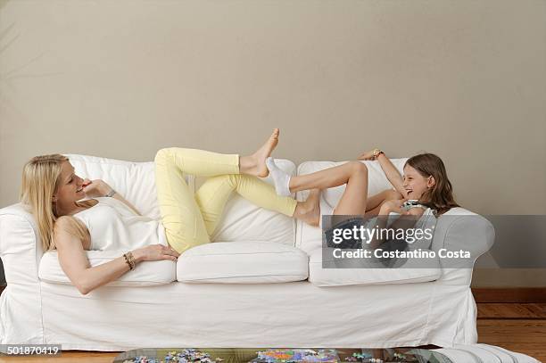 mother and daughter playing footsie on sofa - playing footsie stock pictures, royalty-free photos & images