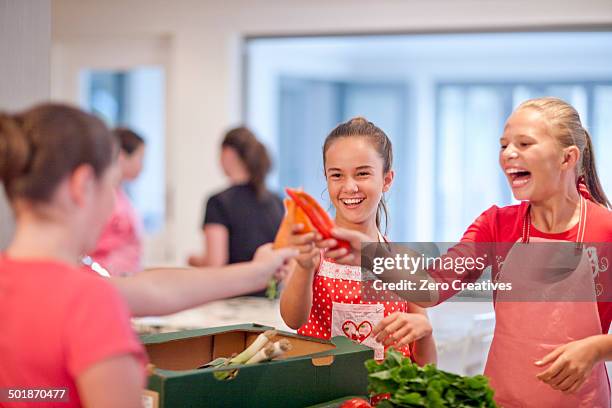 teenage girls holding up chillies and carrot in kitchen - chili cookoff stock pictures, royalty-free photos & images