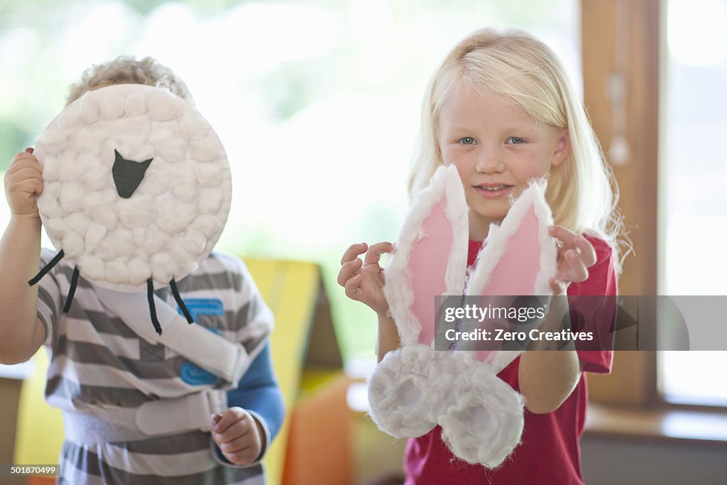 Boy and girl holding up sheep and rabbit creations at nursery school