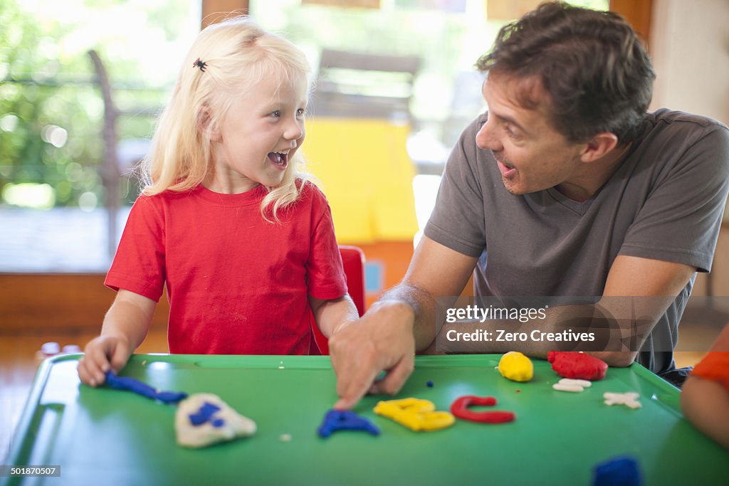 Male teacher and girl learning alphabet at nursery school