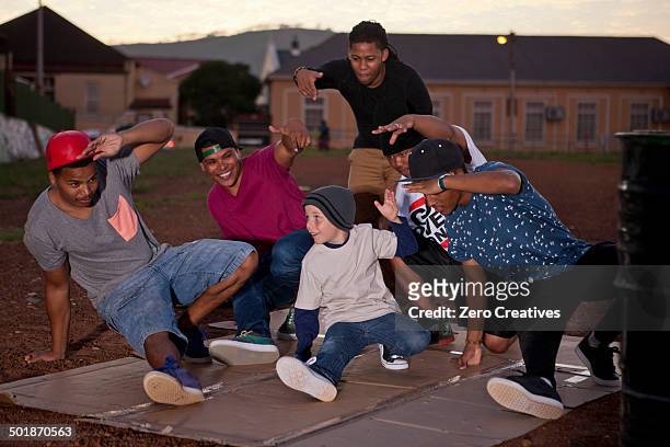 group of adult males and boy breakdancing in park at dusk - hip hop idols stock pictures, royalty-free photos & images