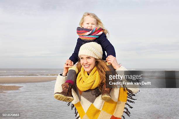 mid adult woman shoulder carrying daughter on beach, bloemendaal aan zee, netherlands - girl scarf bildbanksfoton och bilder