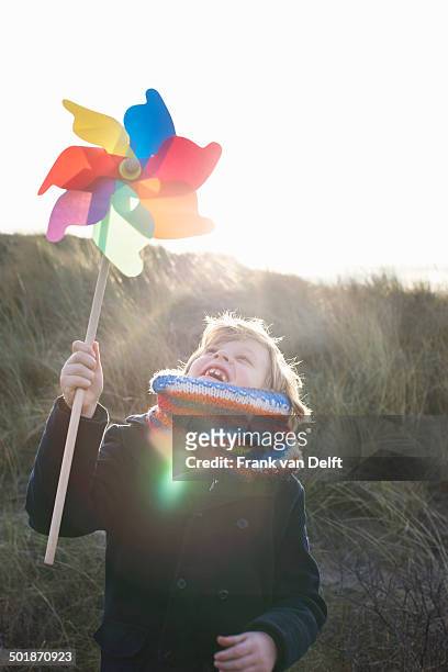 boy holding up paper windmill at coast - 紙風車 ストックフォトと画像