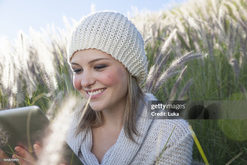 Young woman with digital tablet in long grass