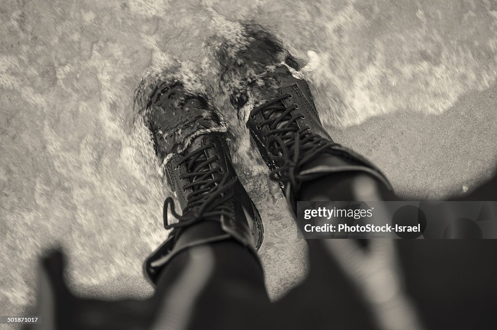 High angle view of young woman in laced boots in sea