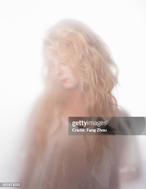 blurred shot of young woman gazing down behind frosted glass - mysterious blond woman stock pictures, royalty-free photos & images