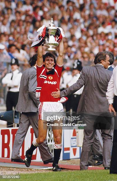 Manchester United captain Bryan Robson holds the trophy aloft as manager Ron Atkinson congratulates him after the 1985 FA Cup Final between...