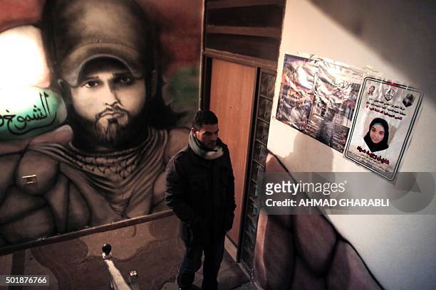 Man walks past a martyr poster of Hadeel Awwad , 14 years old, and a graffiti despecting her brother Mahmud in the hall of the family home in the...