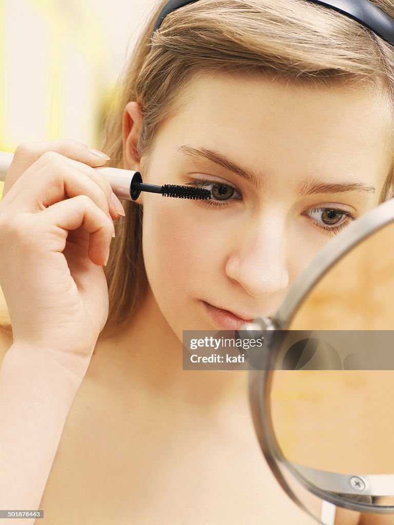 Young woman applying make-up, mascara