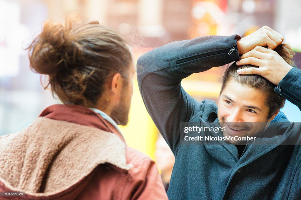 Young man influenced by friend to make a man bun