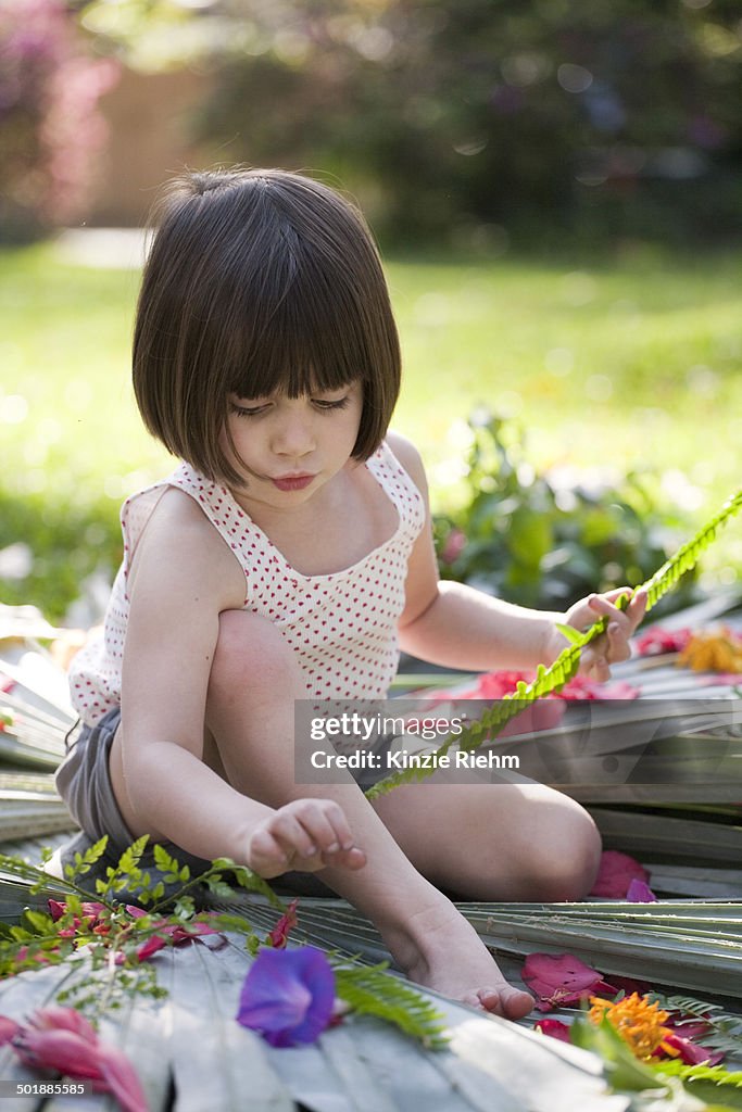 Girl with fern making flower and leaf display in garden