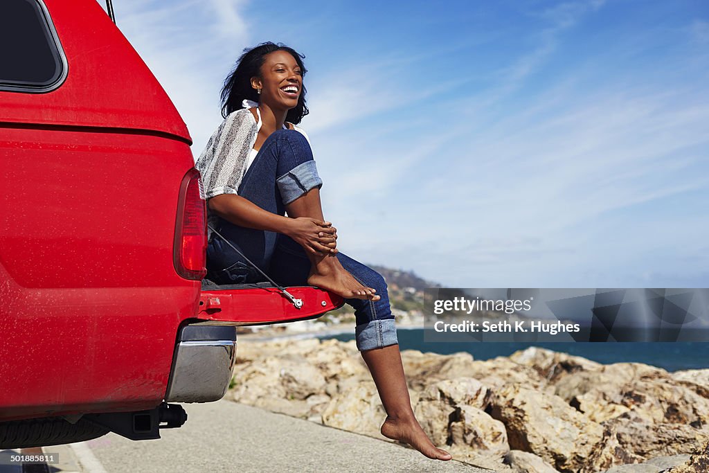 Young woman sitting on car hood, Malibu, California, USA