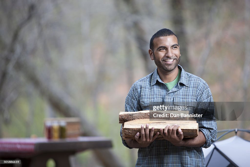 Young man carrying logs on campsite, Sedona, Arizona, USA