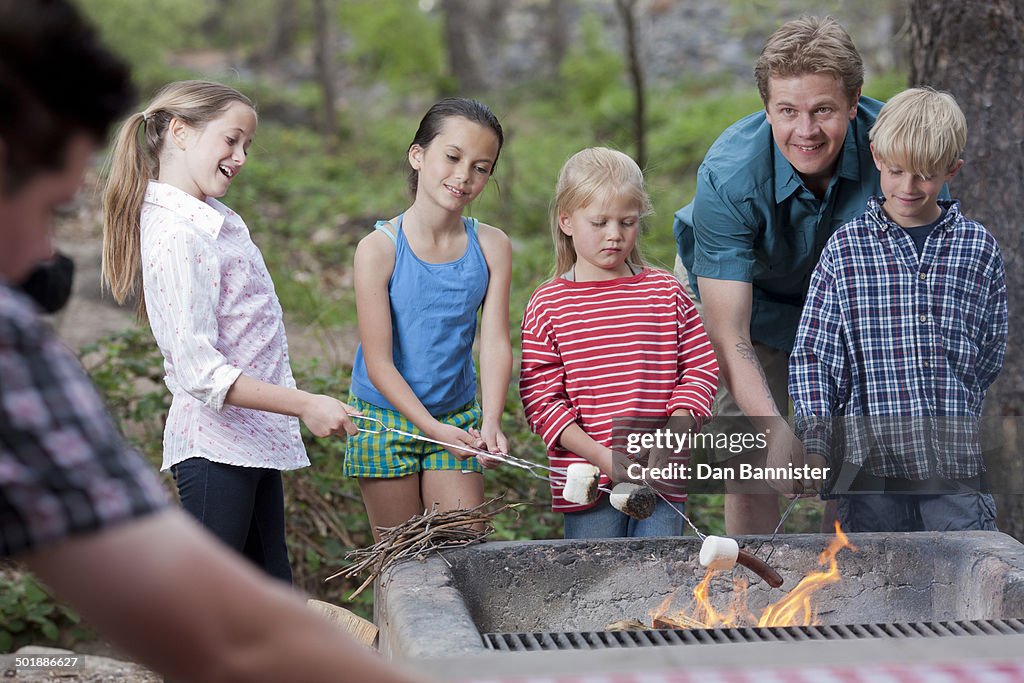 Mature couple and four children toasting marshmallows on campsite, Sedona, Arizona, USA