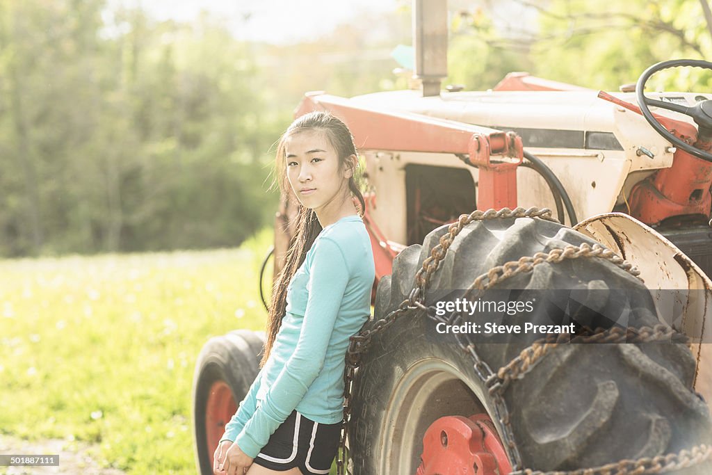 Portrait of teenage girl standing beside tractor