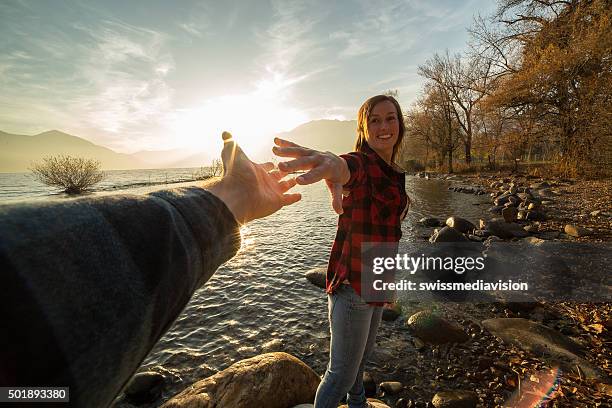 junge frau geht am lake shore bietet ein mann hand - seeufer stock-fotos und bilder