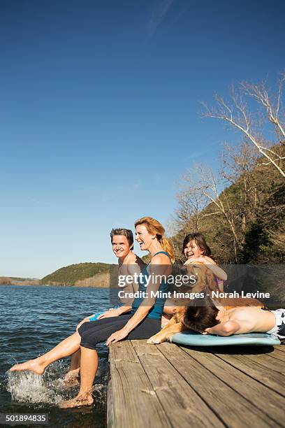 a family and their retriever dog on a jetty by a lake. - eén dier stockfoto's en -beelden