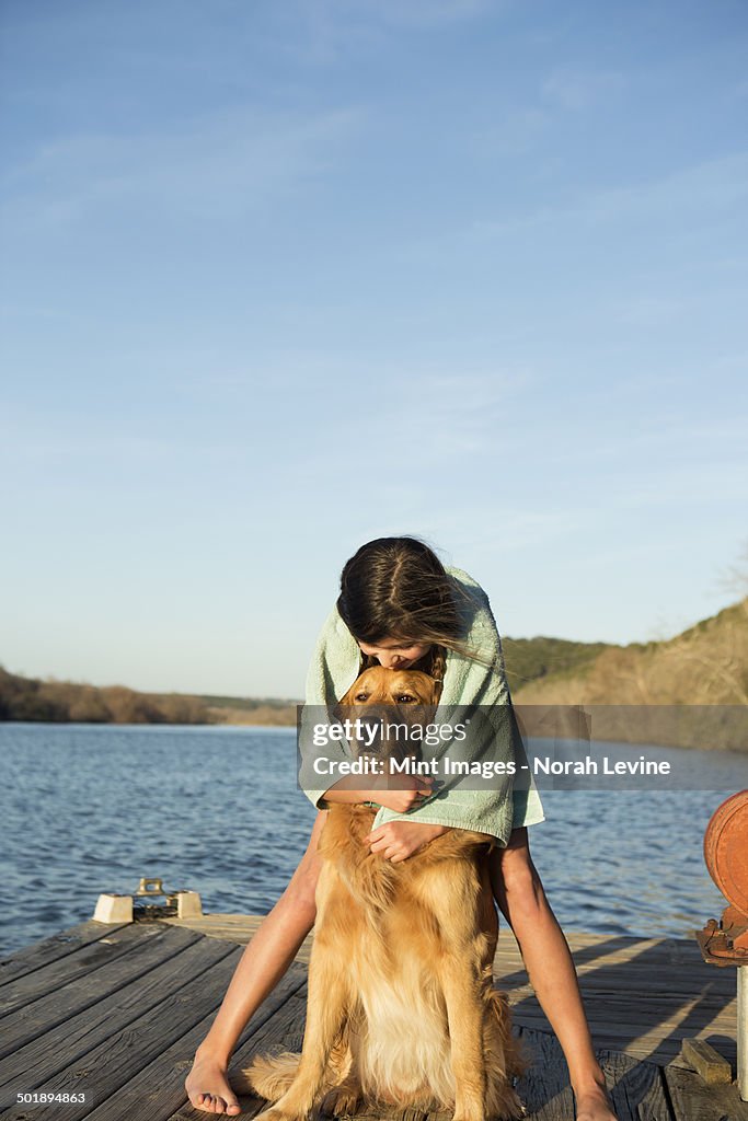 A girl cuddling a golden retriever dog.