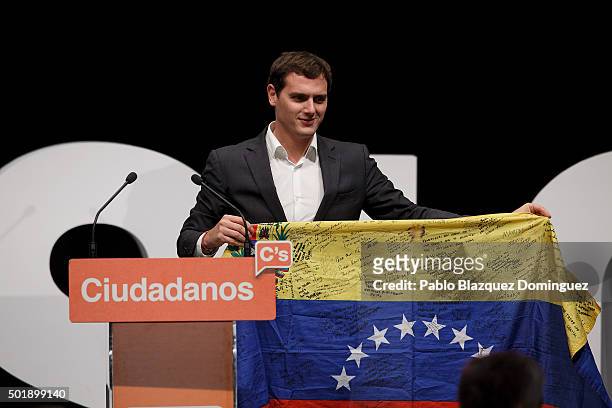 Ciudadanos party leader Albert Rivera holds a Venezuelan flag on stage during the final electoral campaign rally at Plaza de Santa Ana on December...