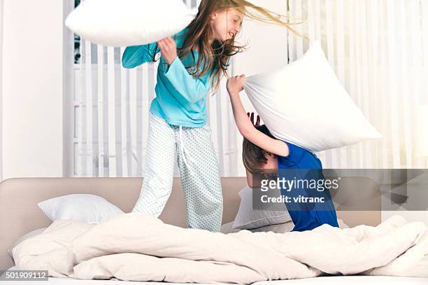children playfighting on parents' bed - pillow fight stock pictures, royalty-free photos & images