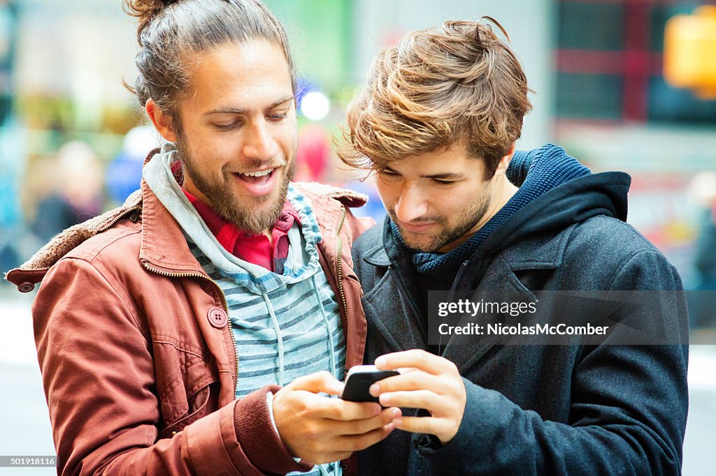 Young man sharing media with friend on mobile phone close-up