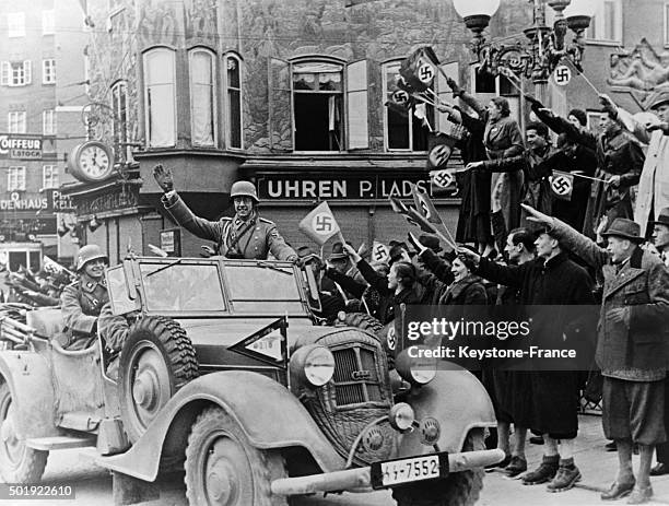 The Salzburg people with nazi flags welcoming a German expeditionary force car with officers on March 14, 1938 in Salzburg, Austria.