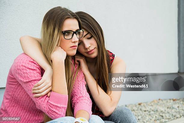 young woman consoling sad friend - unhappy woman blonde glasses stock pictures, royalty-free photos & images