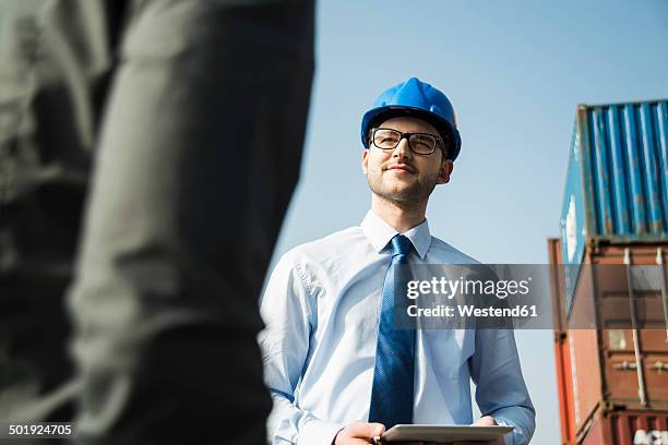 portrait of businessman talking to teenager at container terminal - low angle view of two businessmen standing face to face outdoors stock pictures, royalty-free photos & images