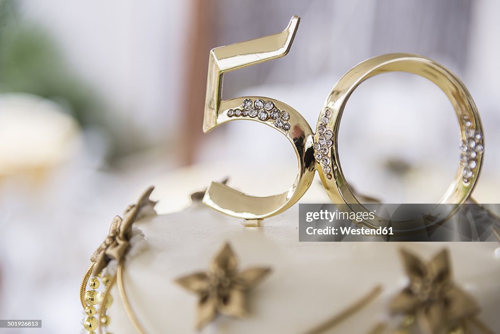 Number 50 in golden plastic attached to the top of a wedding anniversary cake