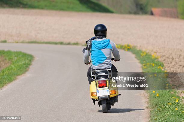 young man driving with his vespa on country road - helmet stock pictures, royalty-free photos & images