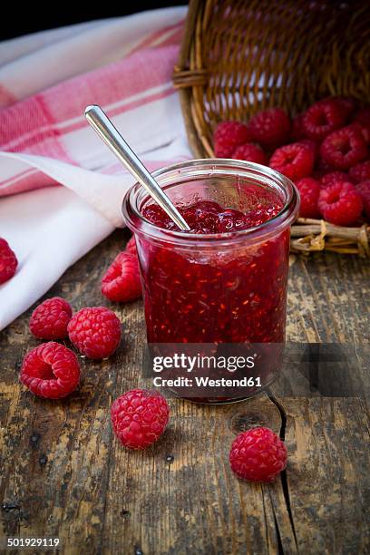 glass of raspberry jam, kitchen towel and raspberries on wooden table - raspberry jam stock pictures, royalty-free photos & images