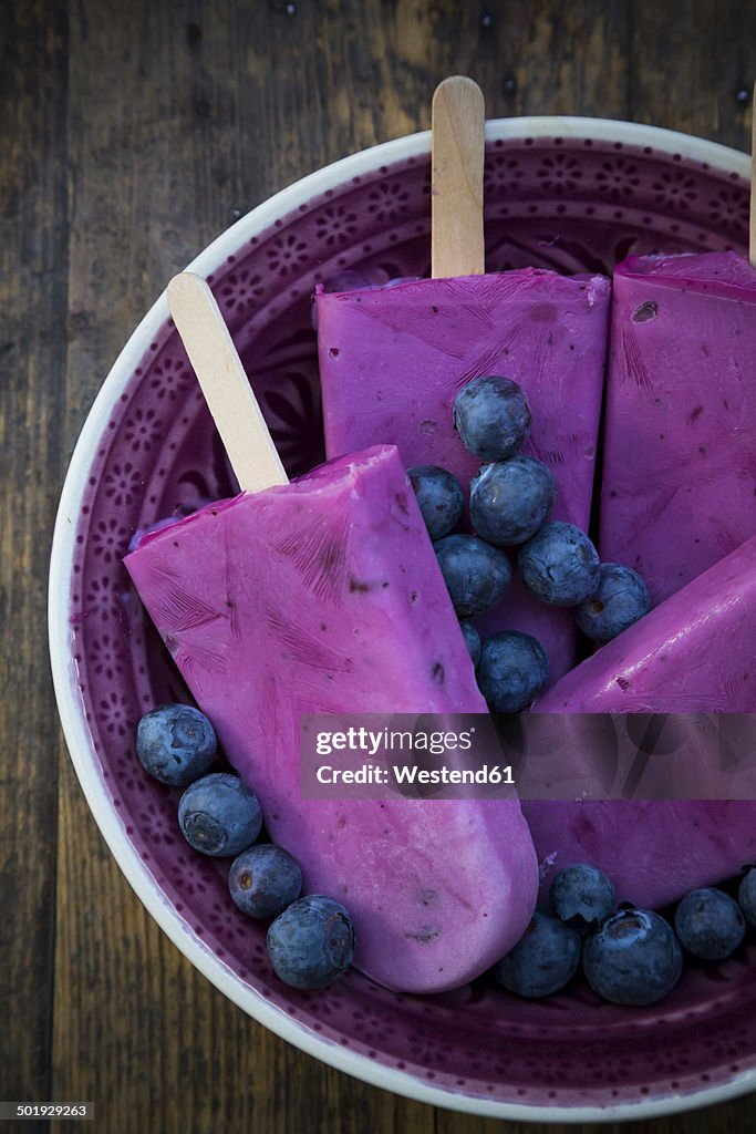 Plate of four yoghurt blueberry ice lollies and blueberries, elevated view