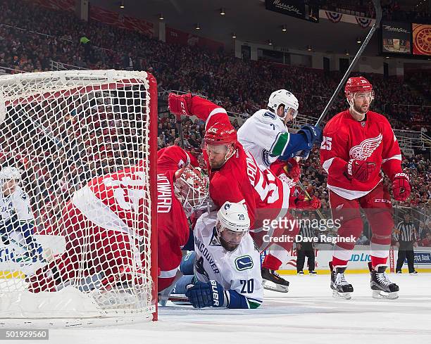 Jimmy Howard of the Detroit Red Wings follows the play as he is tied up by teammate Niklas Kronwall and Chris Higgins of the Vancouver Canucks during...