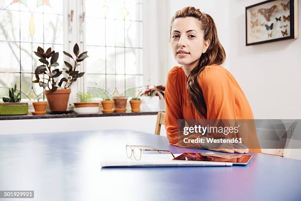 portrait of young woman with tablet computer and newspaper sitting at blue table - dead animal stock pictures, royalty-free photos & images