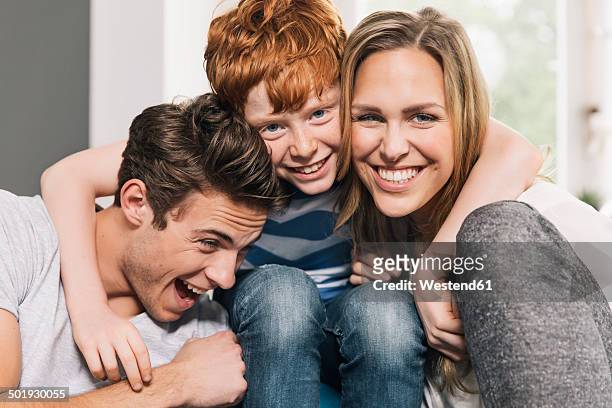 portrait of happy young family sitting on their couch at living room - kids modern stock-fotos und bilder