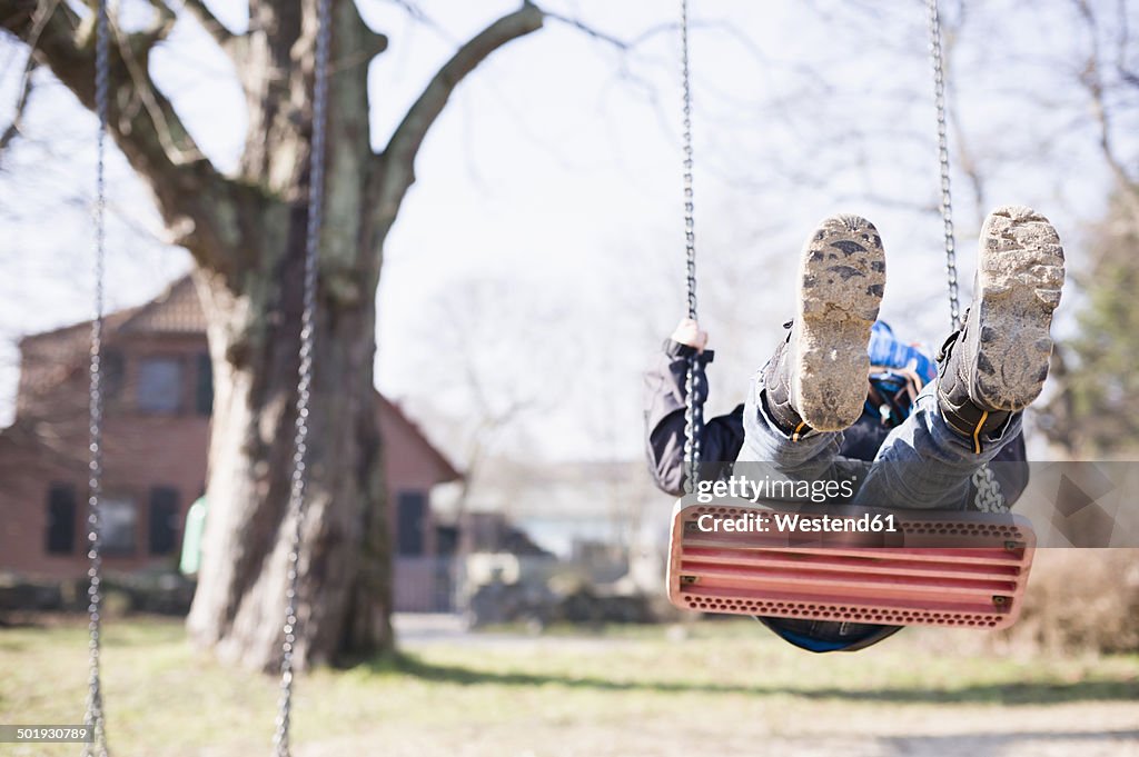 Germany, Mecklenburg-Western Pomerania, Ruegen, little boy swinging at playground