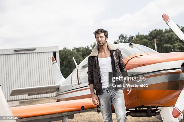 man with leather jacket standing in front of propeller plane - propeller airplane stock pictures, royalty-free photos & images