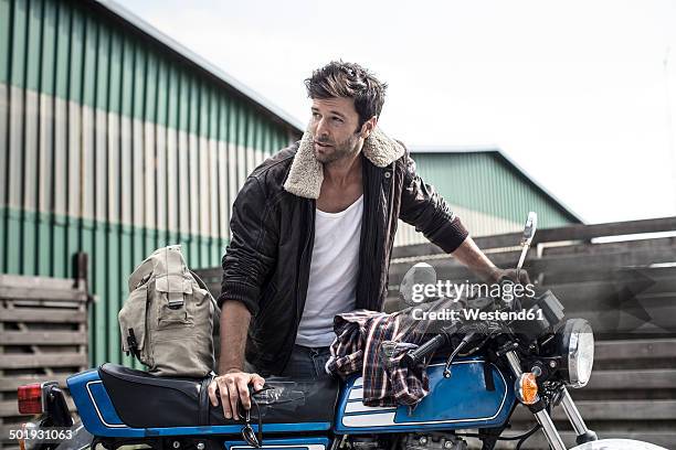 portrait of man leaning on motorcycle - leather jacket stock-fotos und bilder