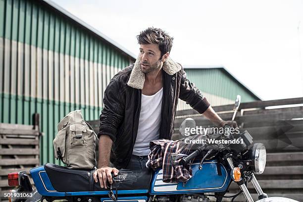 portrait of man leaning on motorcycle - motorcycle man stock pictures, royalty-free photos & images