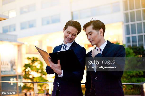 japanese businessmen in tokyo having the working conversation outdoors - map street stockfoto's en -beelden
