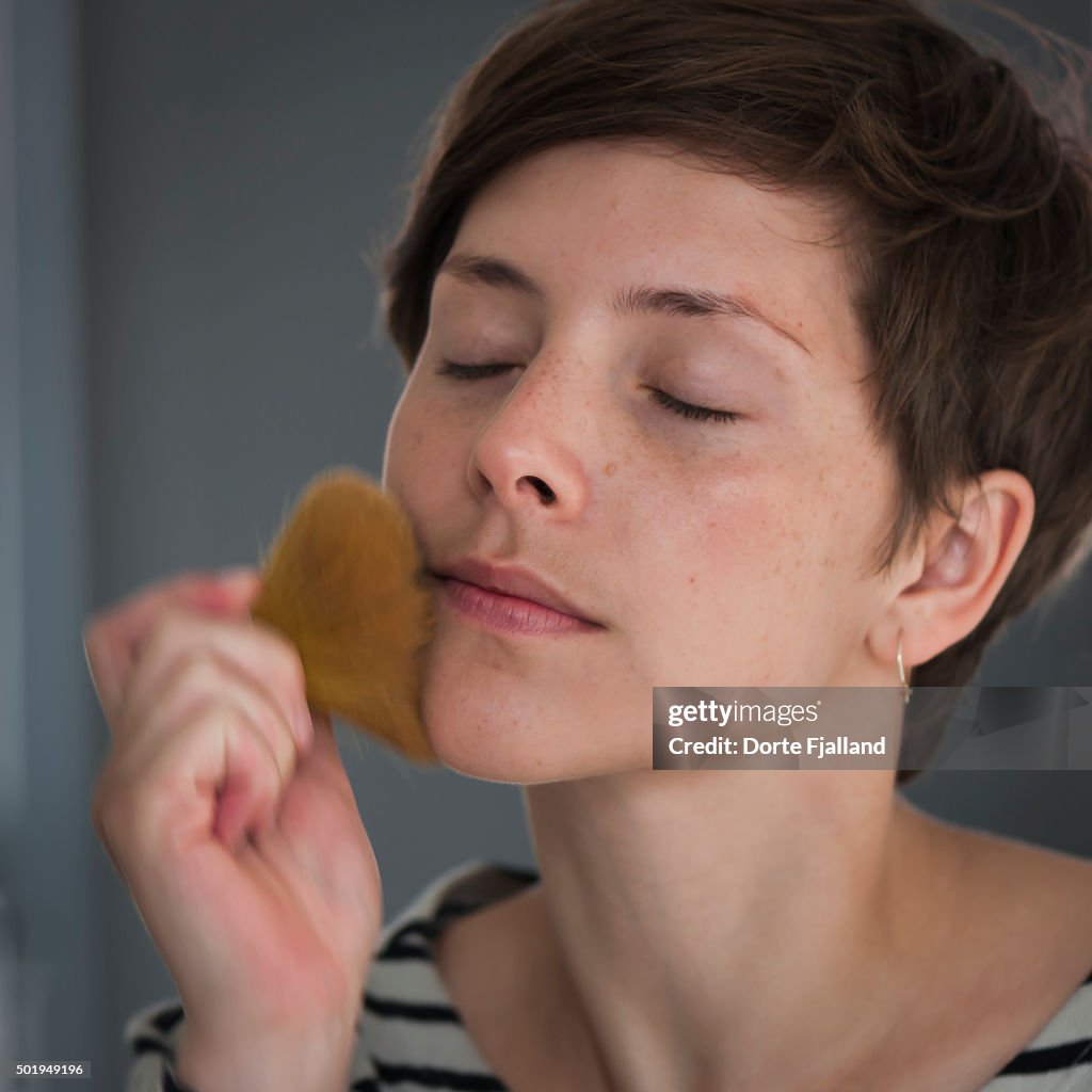 Young woman powdering her face